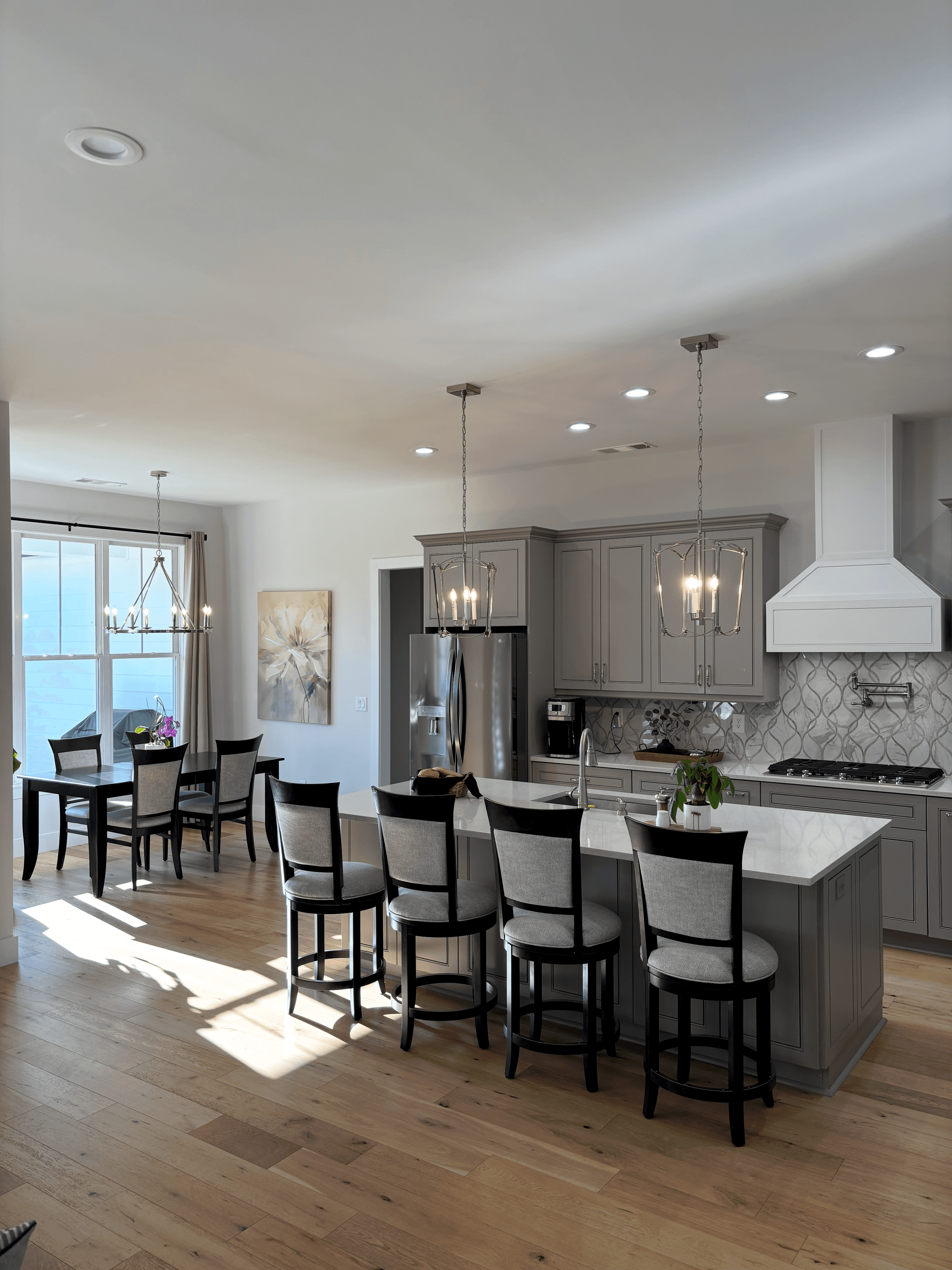 Kitchen renovation with soft gray cabinetry, a large island, dining area, and bright natural light.