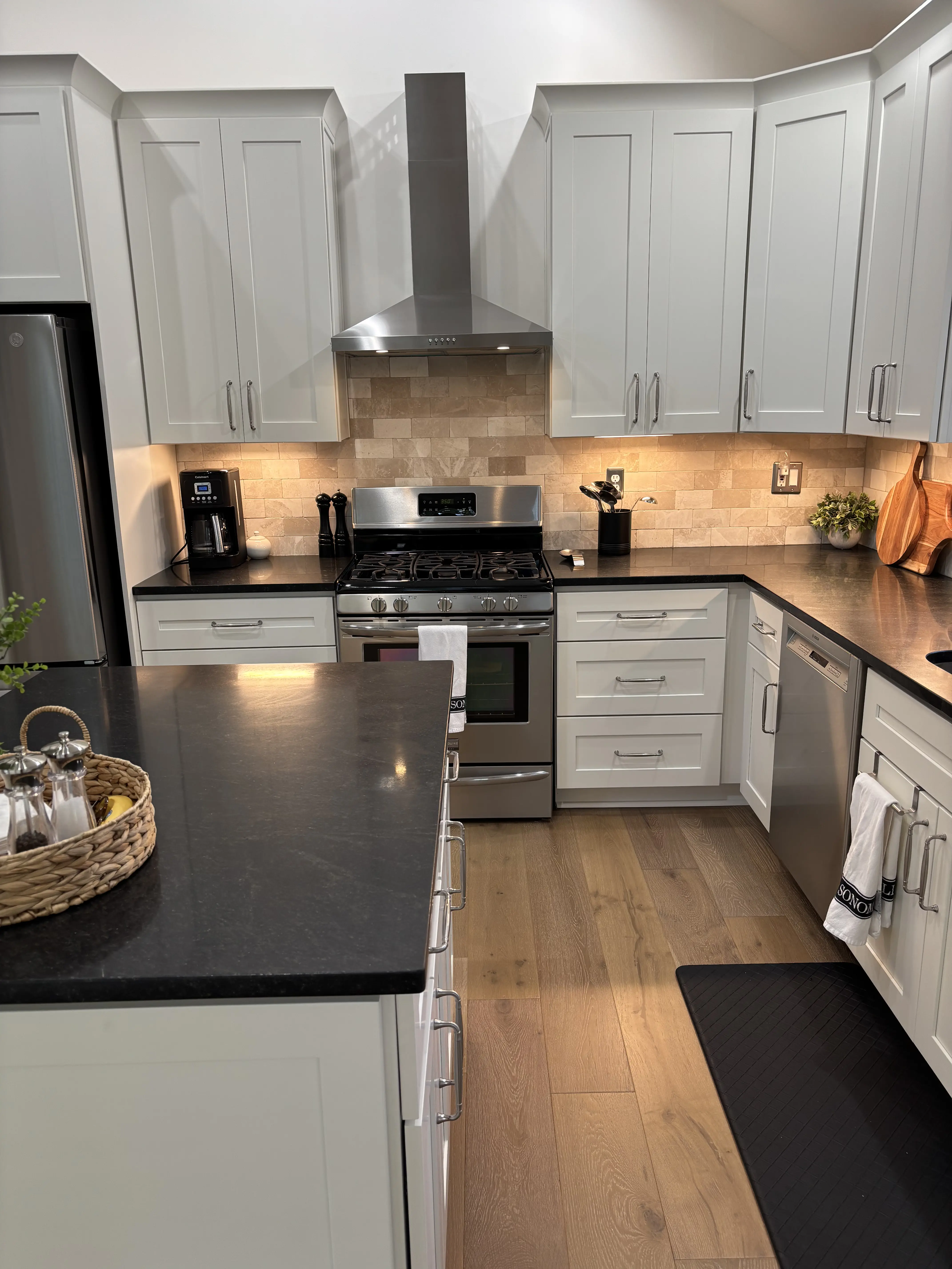 Kitchen renovation with white cabinetry, dark countertops, and a stainless range wall.